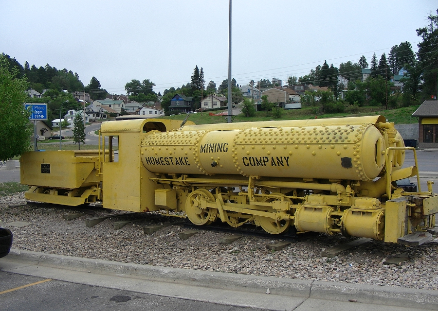 Photo of a yellow compressed air locomotive exhibited on a historic rail segment
