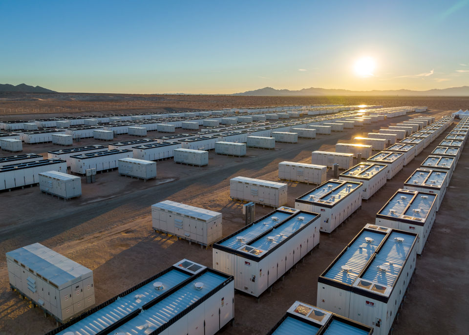 An array of utility-scale battery energy storage containers in the desert.