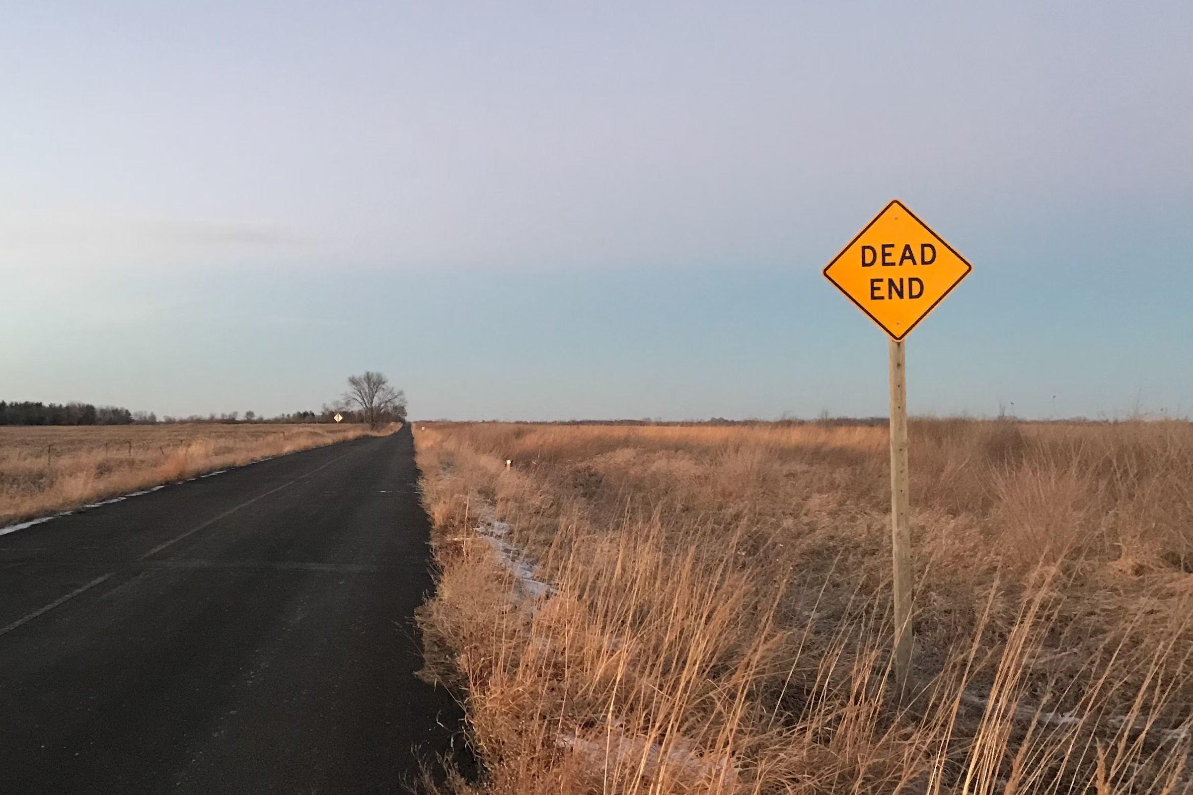 Photo of an empty road with a road sign that says 'Dead end'