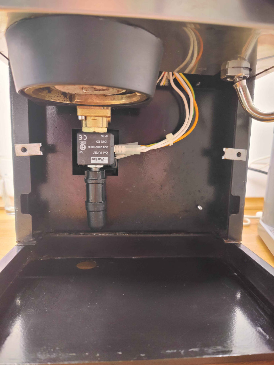Front view of a Rancilio Silvia espresso machine with the lower panel removed and the solenoid valve visible
