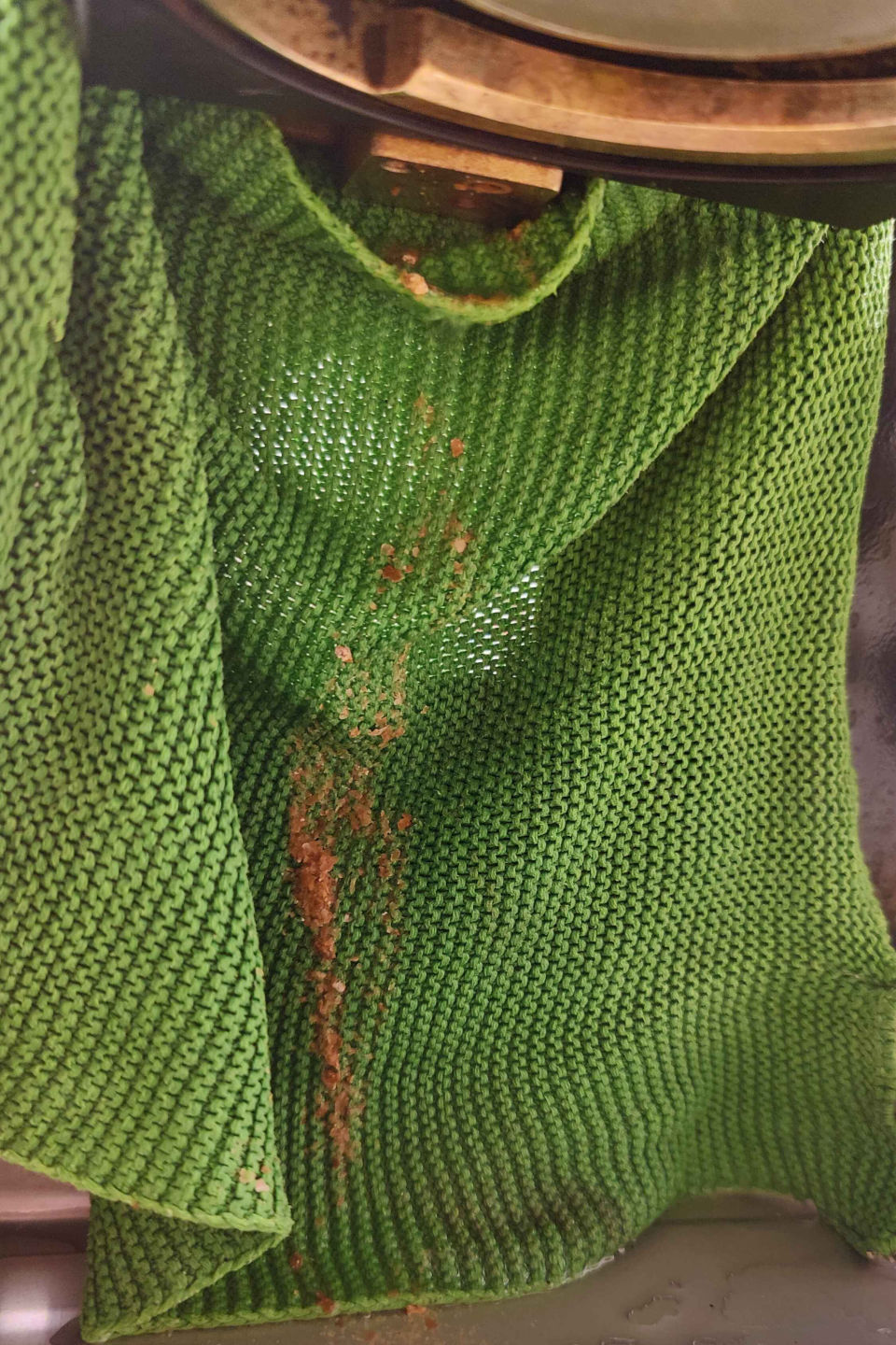 Photo of a green cloth hung below the coffee machine group head and a lot of sludge that came out of a hole and dropped onto the cloth